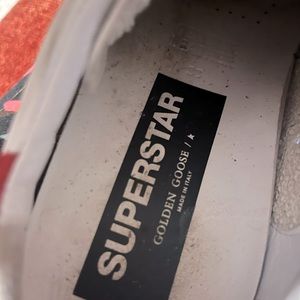 Golden Goose Superstar white with snakeskin star and red tab on heels.